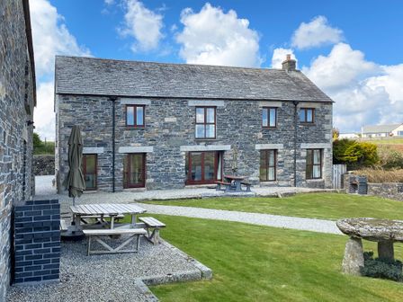 A stone building with windows and a picnic table outside on gravel and grass at Marhayes Camelford