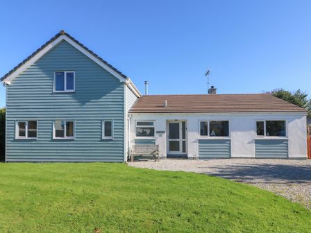 A house with a blue and white exterior and a green lawn at Penhaven in Crackington Haven