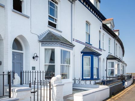 A row of white terraced houses with bay windows and small gated front yards at The Crab Shell in Appledore near Bideford