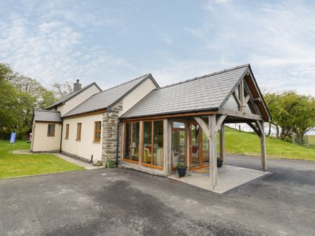 A house with a wooden porch and glass walls on the driveway at Glan Gors in Bylchau near Denbigh