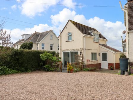 A detached house with a gravel driveway and garden plants at Wisteria Cottage in Exmouth