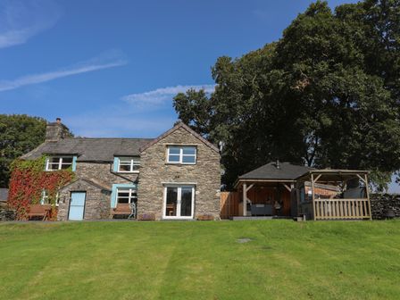 A stone house with blue window frames and a green lawn at Maes Madog in Capel Garmon near Betws-y-Coed