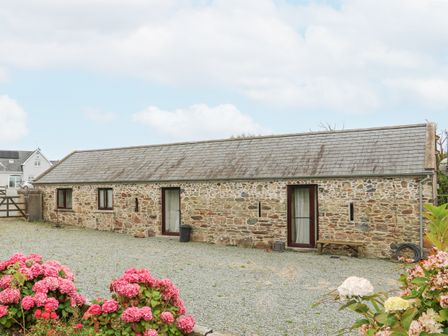 A stone building with two doors and three windows surrounded by gravel and flowers at Swallow's Nest in Tacumshane County Wexford