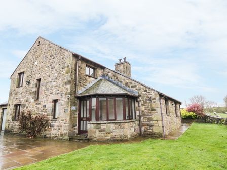 A stone house with multiple windows and a small garden at Hill Bank in Hutton Roof