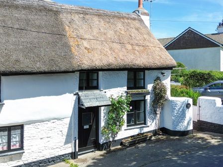 A thatched roof cottage with a door and windows at Easterly Cottage in Bude