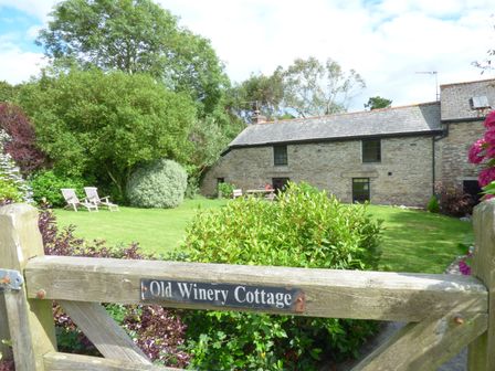 A garden with chairs and bushes outside a stone cottage at Old Winery Cottage Golant near Fowey