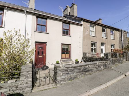 A row of connected houses with stone walls and a small metal gate at Miners Cottage in Blaenau Ffestiniog