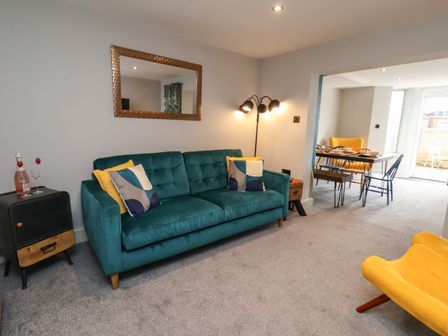 A living room with a green sofa and yellow chairs next to a dining area at Apt 1 @ Hunter's Quay in Bridlington