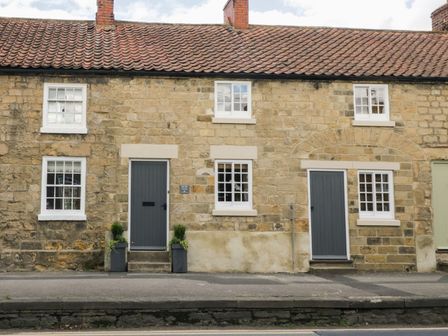 Stone cottages with gray doors and white framed windows along a street at The Old Cartway in Pickering