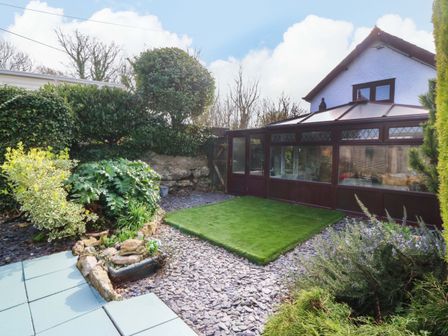 A garden with plants and a conservatory at The Cottage in Marian-Glas