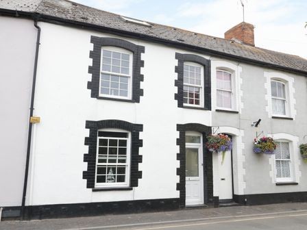A row of terraced houses with hanging flower baskets on a street at No 9 Watchet