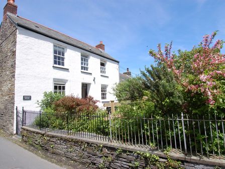 A white two-story house with a front garden and iron fence at Jordan House Boscastle