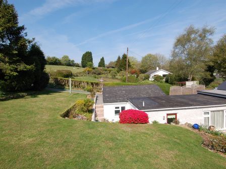 A grassy garden with shrubs and trees surrounding white houses at Trevillas in St Mewan near Polgooth