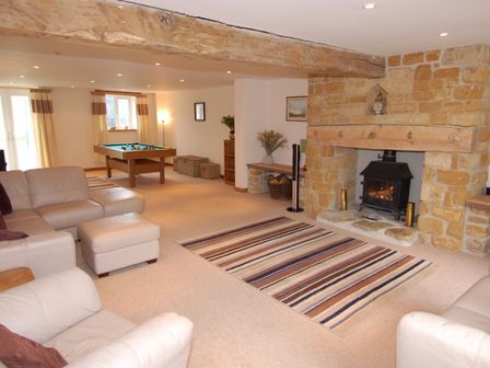 A living room with leather sofas a striped rug a stone fireplace and a pool table at West Perry Hay in North Chideock near Chideock