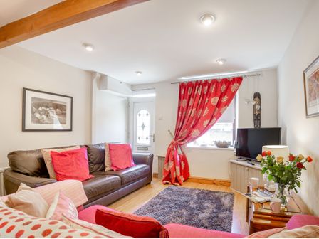 A living room with two sofas a television and a window with red curtains at 40 New Row in Pwllheli