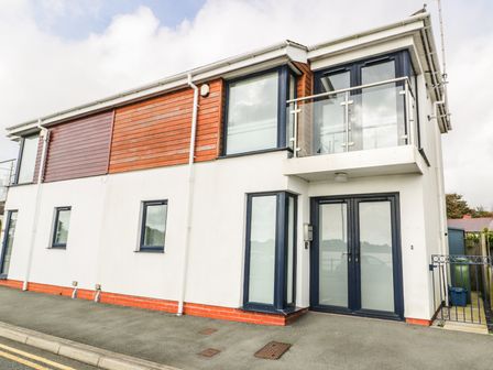 A modern two-story building with glass balcony and large windows at 7 Marina View in Pwllheli