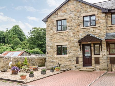 A stone house with a driveway and garden pots at 14 The Maltings in Rothbury