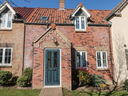 Front view of a brick house with a blue door and windows with white frames at Dotty's Sunshine Cottage in The Bay near Filey