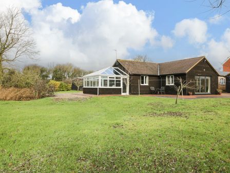 A house with a glass conservatory and lawn in the front at The Annex in Royal Wootton Bassett