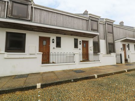 Row of white houses with wooden upper sections and wooden doors along a sidewalk at 4 Bredon Court in Newquay