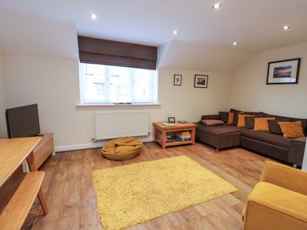 A living room with a sofa and television at Y Enciliad in Rhosneigr
