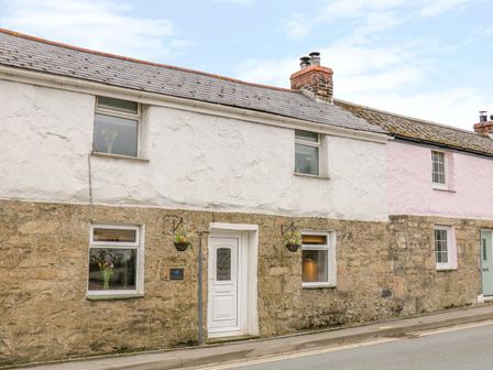 A stone and white plaster house with four windows and a white door on a street at Blue Anchor in Fraddon