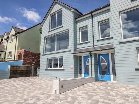 A modern two story residential building with blue doors and large windows in front at Harmon Vale in Solva