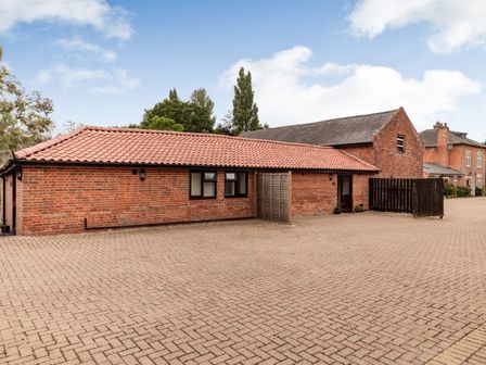 A single-story brick building with a tiled roof and a paved area in front at The Nest Box in Diss