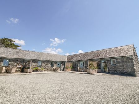 A stone building with multiple doors and windows with outdoor seating and plants at Sisial-y-Mor in Talybont near Barmouth