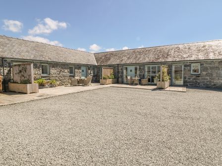 A courtyard with stone buildings and outdoor seating at Bwthyn Bach in Talybont near Barmouth