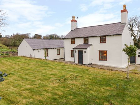 A white two-story house with a slate roof and a grassy yard at Pen Y Bryn Cottage in Llandudno