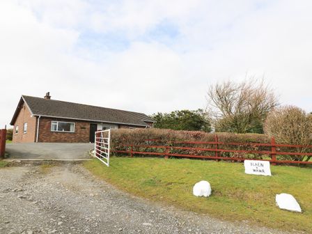 A single story brick house with a sloped roof near a gravel driveway and a gate at Blaenywawr Annexe in Lampeter