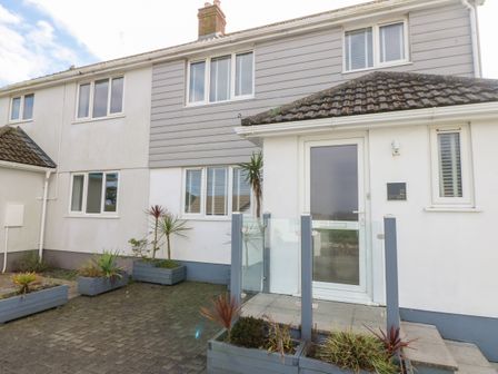 The exterior front entrance of a two story house with white walls and grey cladding at Chy Kerris Carbis Bay