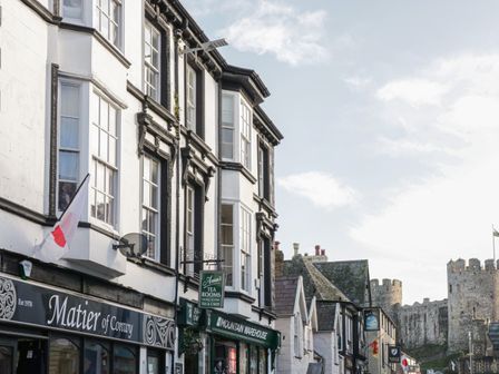 A street view with shops and a castle in the background at Castle Apartment in Conwy