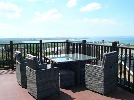 A seating area with a table and chairs overlooking the sea at Maesawel Studio in Llanfair