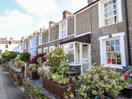 A row of terraced houses with flower planters and shrubs in front at Pump Cottage 8 Glyn Terrace Porthmadog