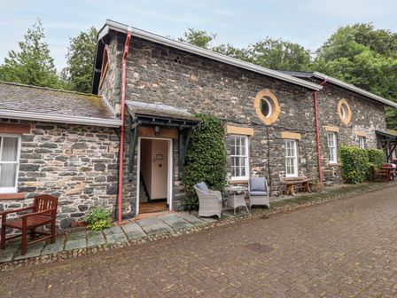 Exterior view of a stone building with windows and outdoor seating at The Hayloft in Thirlmere