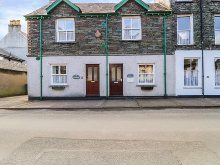 Front view of stone and stucco terraced houses with wooden doors and windows at Swinside Cottage Keswick