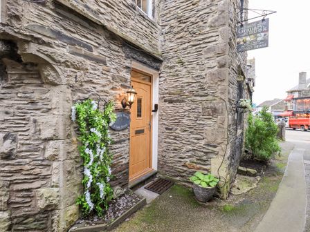 Stone exterior wall with wooden door and potted plants at Granary Nook in Windermere