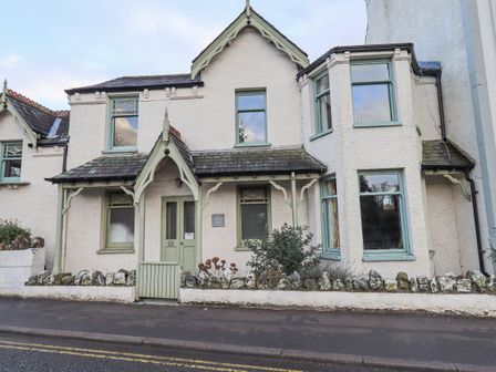 The exterior of a two story house with green framed windows and a small front garden at Greta Mill in Keswick