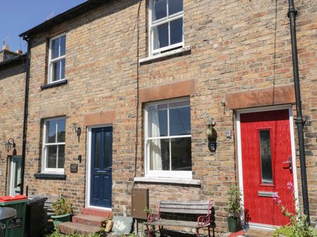 Brick terraced houses with blue and red doors and windows on a sunny day at Banks Place in Keswick