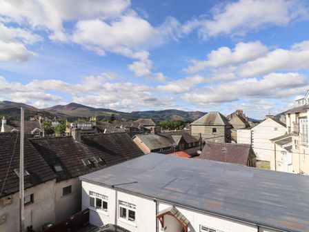 Roofs of houses with hills in the background under a partly cloudy sky at Sky View in Keswick