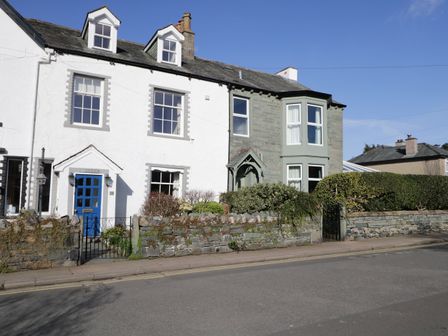 A house with a white and stone facade, blue door, front garden with stone wall and hedge at White House in Keswick