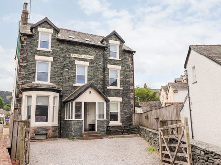 A stone house with white window frames and a porch surrounded by a gravel yard at Latrigg House in Keswick