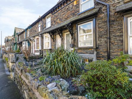 A row of stone houses with small front gardens and plants along a street at Mrs Puddleducks in Windermere