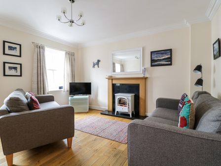 A living room with two gray sofas a wall-mounted mirror above a fireplace and a television at Siskin in Keswick