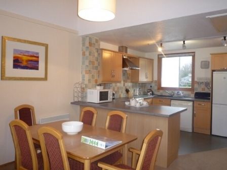 A kitchen and dining area with a wooden table and chairs a microwave countertop appliances and a window at 17 Keswick Bridge in Keswick