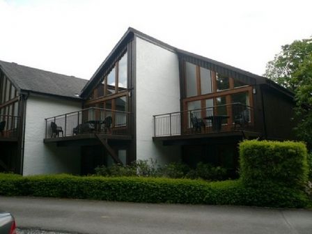 A modern multi-unit building with balconies and glass windows surrounded by greenery at 10 Keswick Bridge in Keswick