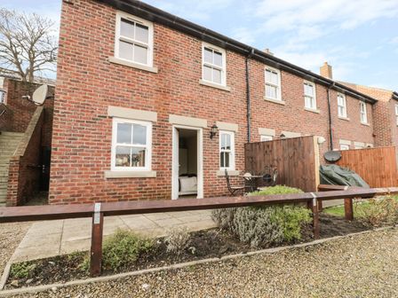A brick house with four windows and a door opening to a patio with a table and chairs at Platform 12 in Whitby