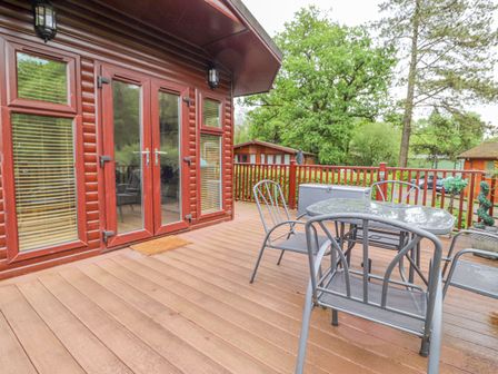 A wooden deck with metal chairs and a table outside a cabin at 10 Thirlmere White Cross Bay near Troutbeck Bridge